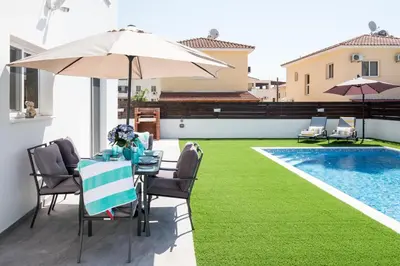a patio with a table and an umbrella and a pool at Voroklini Villa with Pool in Larnaka