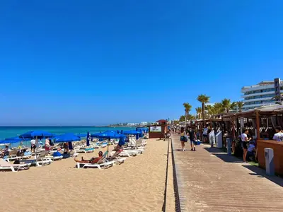 a beach with people sitting on chairs and umbrellas at Luxury 2-floor Villa with Private Swimming Pool in Paralimni