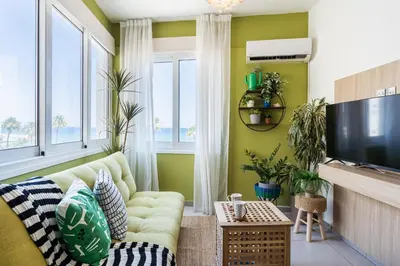 a living room with a couch and a tv at Whispering Palms 1-BR Apt By Finikoudes Beach in Larnaka