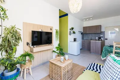 a living room with a flat screen tv and plants at Whispering Palms 1-BR Apt By Finikoudes Beach in Larnaka