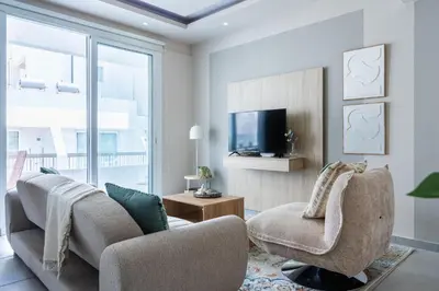 a living room with two chairs and a tv at Beach Daze 1-BR Apt By Finikoudes Beach in Larnaka