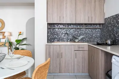 a kitchen with wooden cabinets and a table at Beach Daze 1-BR Apt By Finikoudes Beach in Larnaka