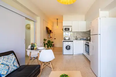 a small kitchen with a white refrigerator and a table at Sea Breeze 1-BR Apt in Pyla in Pyla