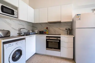 a kitchen with white cabinets and a washer and dryer at Sea Breeze 1-BR Apt in Pyla in Pyla