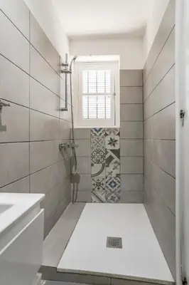a bathroom with a shower with a sink and a window at To Hani - Small Studio in Nicosia