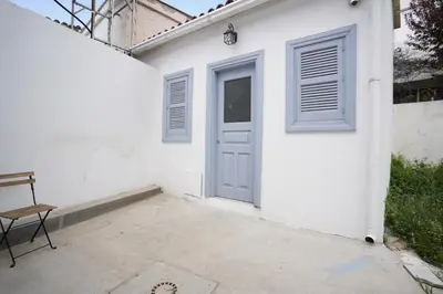 a white house with a blue door and a chair at To Hani - Small Studio in Nicosia