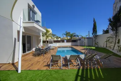 a backyard with a pool and chairs and a house at Tsokkos Family Villa - Pool Garden 2' Walk to Beach in Protaras