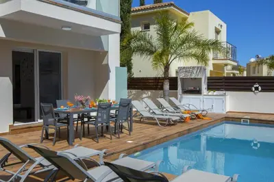 a patio with a table and chairs next to a swimming pool at Tsokkos Family Villa - Pool Garden 2' Walk to Beach in Protaras