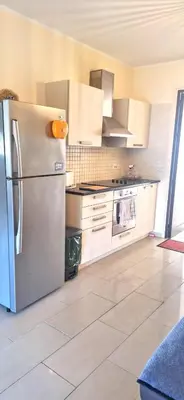 a kitchen with a stainless steel refrigerator and white cabinets at AFRODITI APARTMENTs in Pervolia