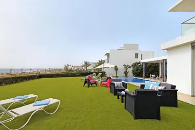 a patio with lawn chairs and a swimming pool at Villa Napa Seaside in Ayia Napa