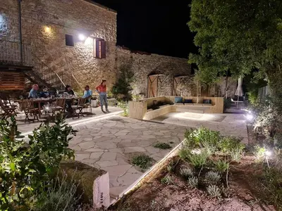 a group of people sitting at tables in a courtyard at night at myLofou in Lofou