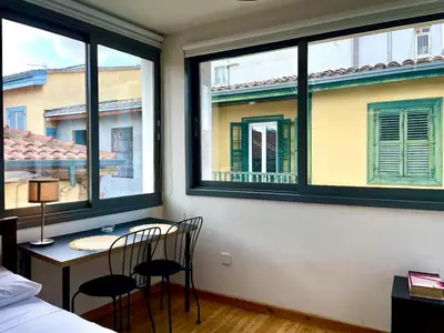 a bedroom with two chairs and a table and two windows at Irida - Studio Down Town Nicosia in Nicosia