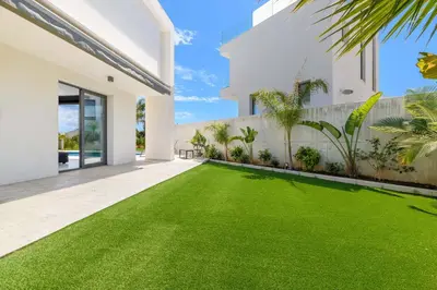 a yard of green grass in a white house at By The Beach - Royal Sapphire Villa in Protaras