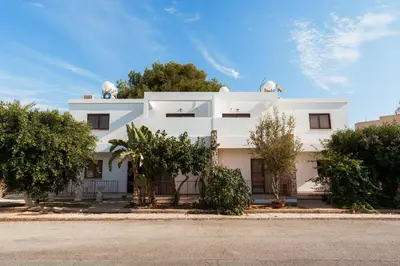 a white building with trees in front of it at SerenityOne - Centrally located One Bedroom Apt in Ayia Napa