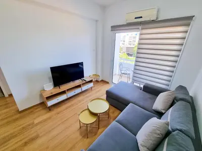 a living room with a blue couch and a flat screen tv at Springfield Park Apartment in Larnaka