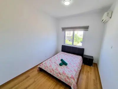 a bedroom with a bed in a room with a window at Springfield Park Apartment in Larnaka