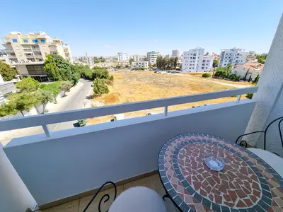 a balcony with a table and a view of a street at Springfield Park Apartment in Larnaka