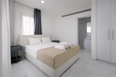a white bedroom with a bed with towels on it at Mediterranean Dream Beachfront Villa in Larnaka