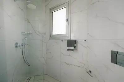 a white bathroom with a shower and a window at Mediterranean Dream Beachfront Villa in Larnaka