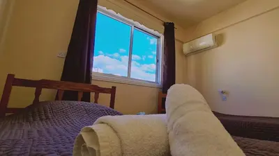 a bedroom with a bed and a window with a blanket at STAY Chill n' Joy in Ayia Napa