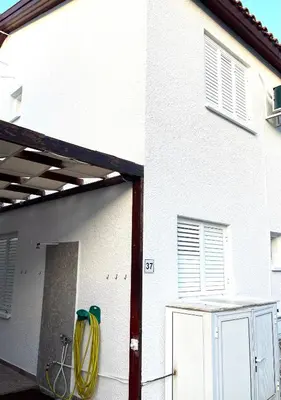 a white house with a garage with a yellow hose at The Mediterranean Sea at your doorstep!! in Meneou