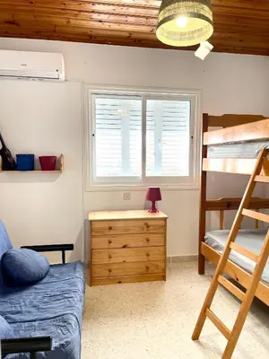a bedroom with a bunk bed and a desk with a lamp at The Mediterranean Sea at your doorstep!! in Meneou