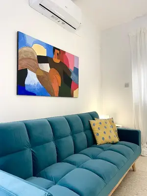 a blue couch in a living room with a painting at The Mediterranean Sea at your doorstep!! in Meneou