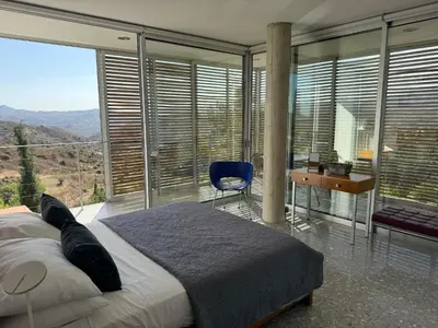 a bedroom with a bed and a desk and windows at Luxury Villa Pluto Stunning Mountain Views in Ora