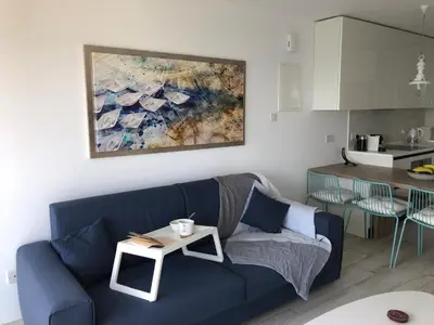 a living room with a blue couch and a kitchen at Blue Escape (Beach Seafront) in Larnaka