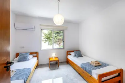 two beds in a room with a window at Maistralli Villa in Protaras