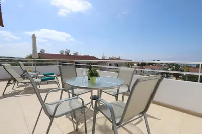 a table and chairs on the roof of a balcony at Nissi 3 Amazing Sea View Apartment in Ayia Napa