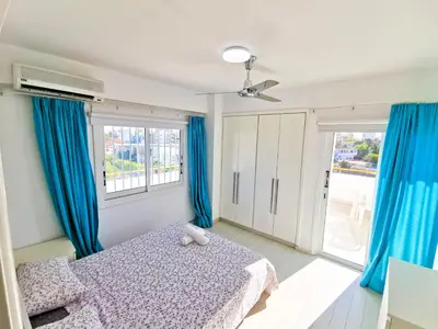 a bedroom with blue curtains and a bed and a window at Sun Kissed Apartment in Larnaka