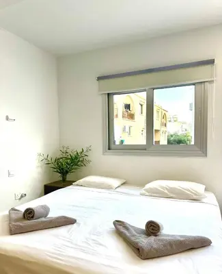 a bedroom with a large white bed with a window at Serene Napa Suites - Heart of Ayia Napa in Ayia Napa