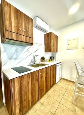 a kitchen with wooden cabinets and a sink at Serene Napa Suites - Heart of Ayia Napa in Ayia Napa