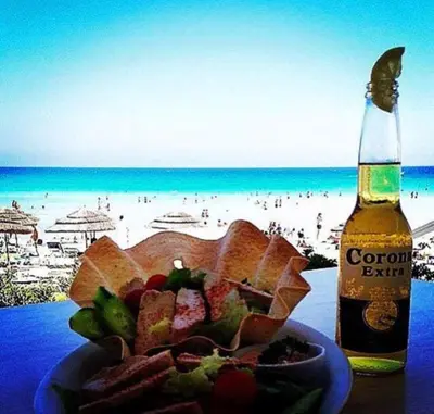 a plate of food and a bottle of beer next to a beach at Villa millie Cyprus in Protaras
