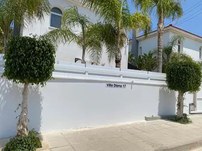a white wall with palm trees in front of a house at Villa Diana - 200 meters from Kapparis, Fireman's Beach in Paralimni