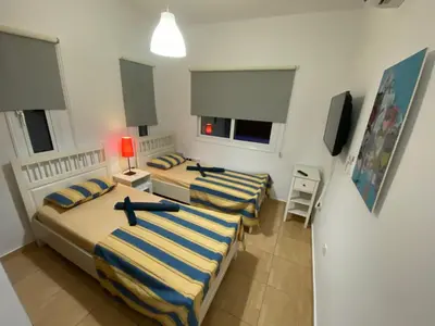 a bedroom with two beds and a tv in it at Villa Diana - 200 meters from Kapparis, Fireman's Beach in Paralimni