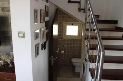 a bathroom with a toilet and a staircase with a door at Immaculate 3-Bed House in Pentakomo in Pendakomo