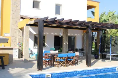 a wooden pergola with a table and chairs next to a pool at Immaculate 3-Bed House in Pentakomo in Pendakomo