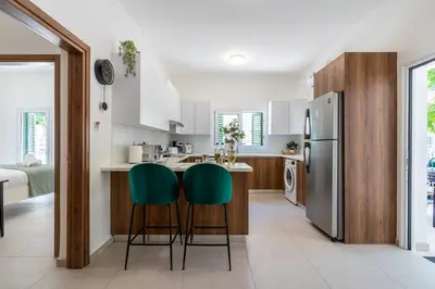 a kitchen with white cabinets and green bar stools at Arty Haven - Spacious 3-BR House in Larnaca in Larnaka