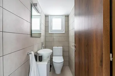 a bathroom with a toilet and a sink and two windows at Arty Haven - Spacious 3-BR House in Larnaca in Larnaka