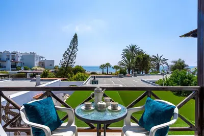 a balcony with a table and chairs and the ocean at Seawaves 1- Bedroom Apartment near Meneou Beach in Larnaka