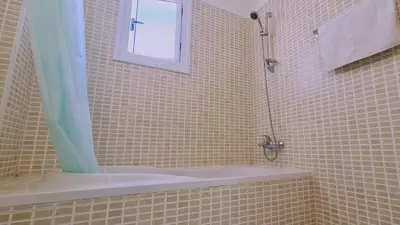 a bathroom with a shower with a tub and a window at Nissi 3 Privileges Apt in Ayia Napa