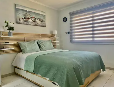 a bedroom with a bed with a green comforter and a window at Dene Hollow Ayia Napa in Ayia Napa