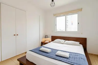 a bedroom with a bed with white cabinets and a window at Carisa DownTown with Rooftop pool in Larnaka