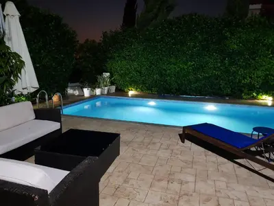 a swimming pool at night with a couch and a chair at Helene Villa in Protaras