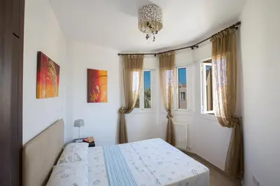 a bedroom with a bed and two windows at Antonia Villa in Protaras
