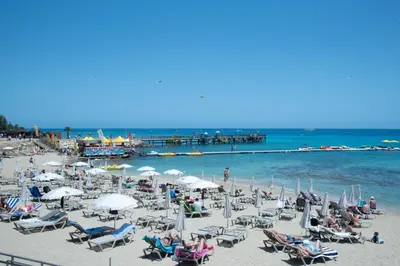 a beach with chairs and umbrellas and a pier at Flisvos Beach Apartments in Protaras