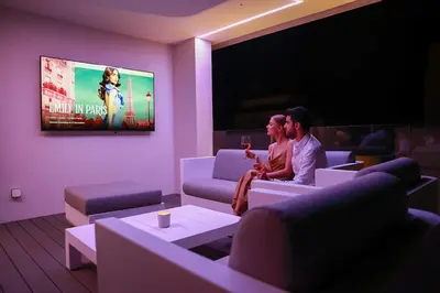 two people sitting in a living room watching a movie at Mythical Villas Zeus and Venus in Protaras