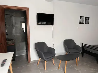 a living room with two chairs and a table and a television at Maria's Apartment 2 in Galata